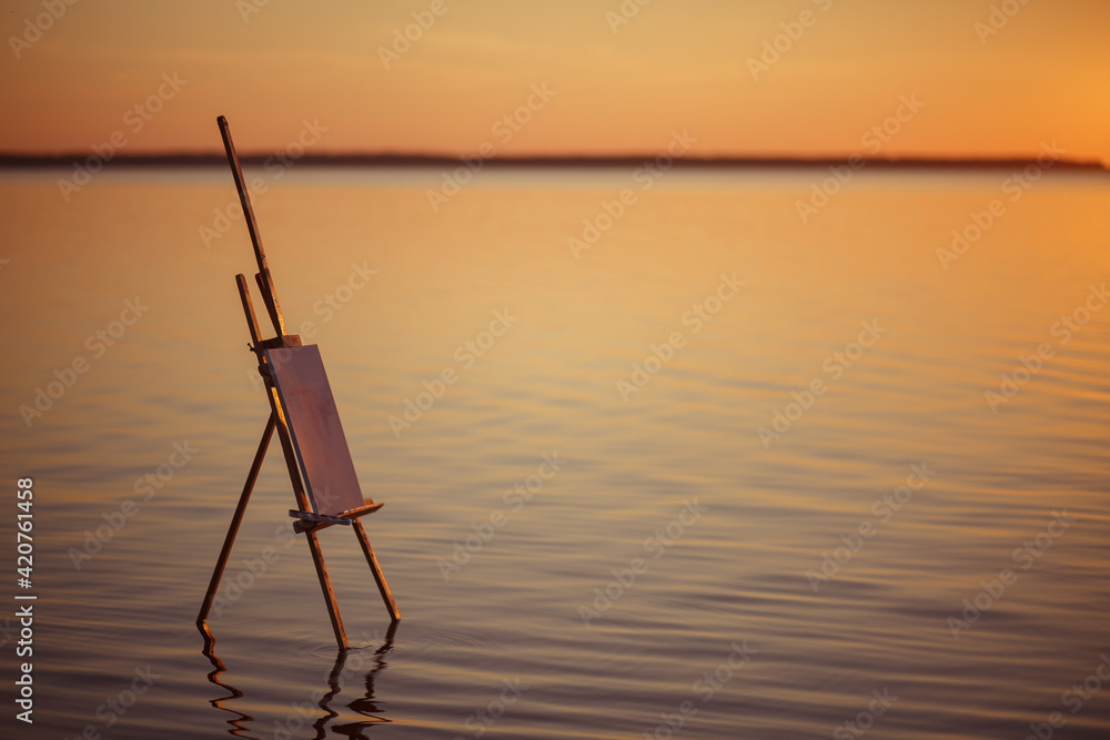 Large salt lake. A wooden easel stands in the water without waves and casts a reflection on the surface. Drawing pictures on the nature. Outdoor hobbies by the sea