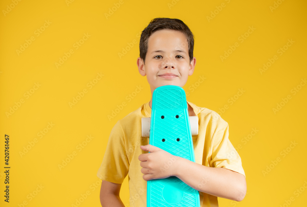 Full length portrait of an adorable young boy riding a skateboard isolated against yellow background Full length portrait of an adorable young boy riding a skateboard isolated against yellow background