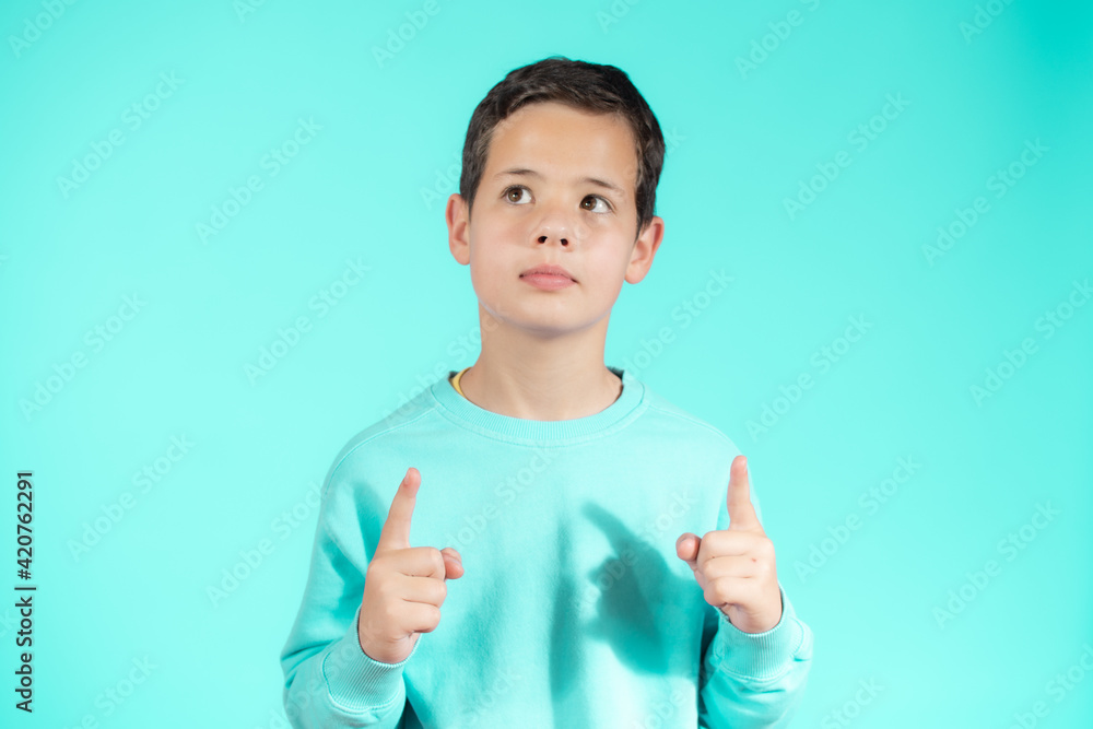 Portrait of cheerful boy with good idea - isolated over green background. 10 year old kid pointing finger up. Child points by fingers upward. Cheerful boy shows something Portrait of cheerful boy with good idea - isolated over green background. 10 year old kid pointing finger up. Child points by fingers upward. Cheerful boy shows something