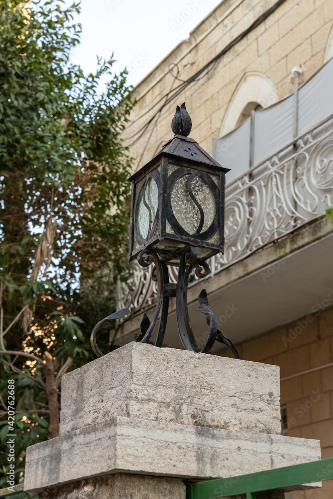 Evening  view of a decorative street lamp installed near a residential building on Hovevei Tsiyon Street in the old district of Jerusalem Talbia - Komiyum in Jerusalem, Israel