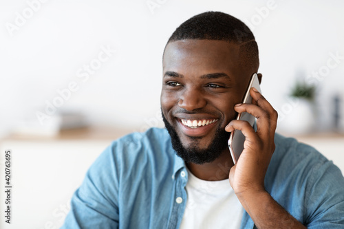 Pleasant Call. Positive Millennial Black Man Talking On Mobile Phone And Smiling