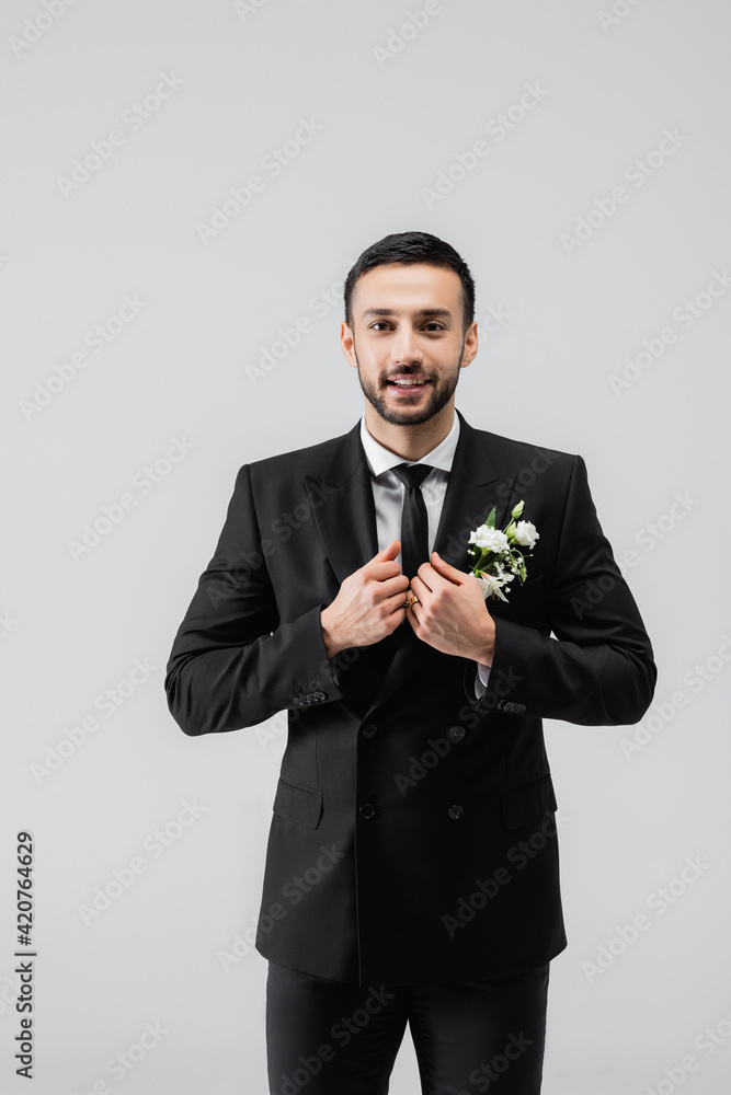 Positive muslim groom in formal wear looking at camera isolated on grey Positive muslim groom in formal wear looking at camera isolated on grey