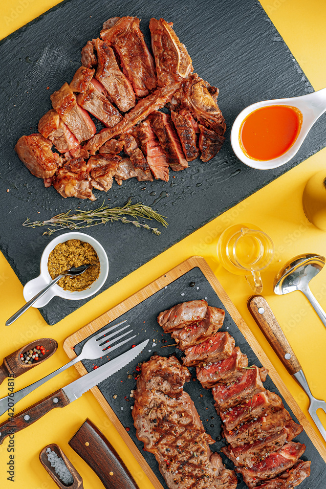two steaks striploin and t-bon, medium rare, on a stone background. dinner concept for two