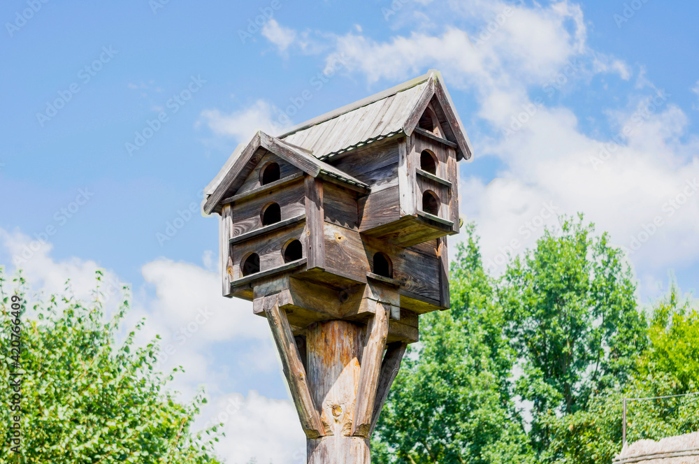 Wooden rural bird feeder with multiple entrances.