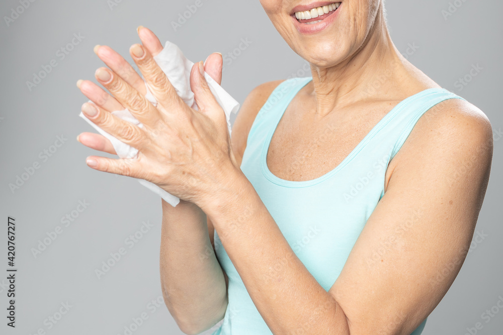Senior woman cleaning hands with wet wipes - care for health and prevention of infectious diseases
