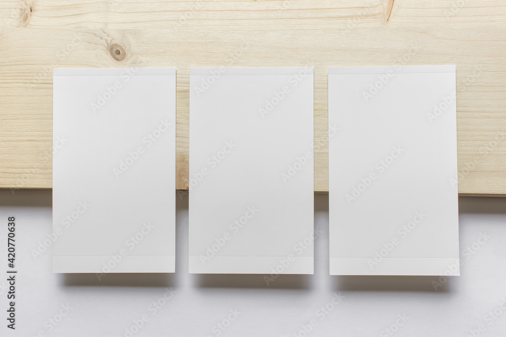 Mockup template with three vertical blank photo cards on wooden and white paper background. Mockup template with three vertical blank photo cards on wooden and white paper background.