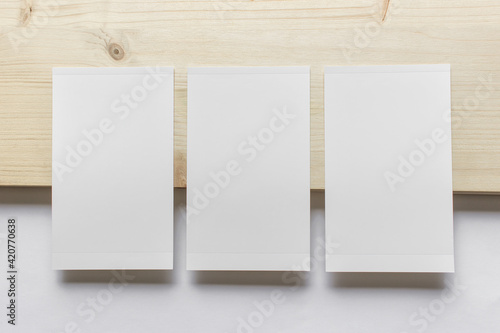 Mockup template with three vertical blank photo cards on wooden and white paper background.