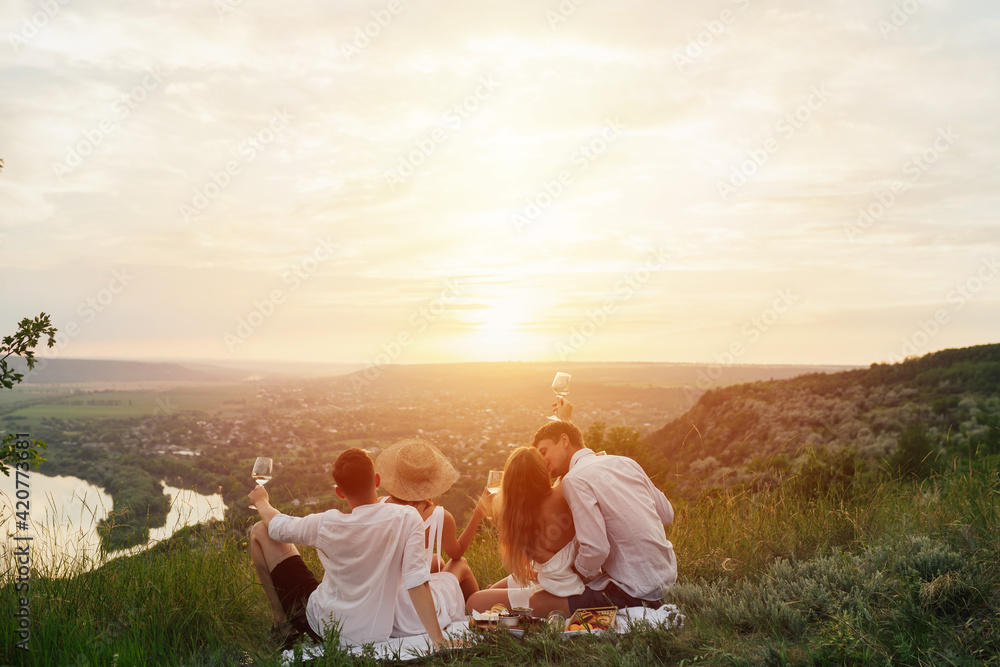 Picnic for couples. Back view of young couples spend time outdoors at picnic at sunset.