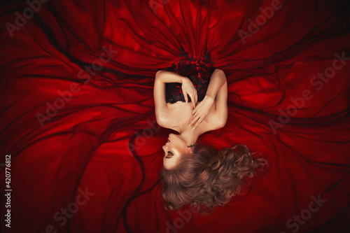 Fototapete Portrait of a reclining beautiful blonde girl in a dark red ball gown
