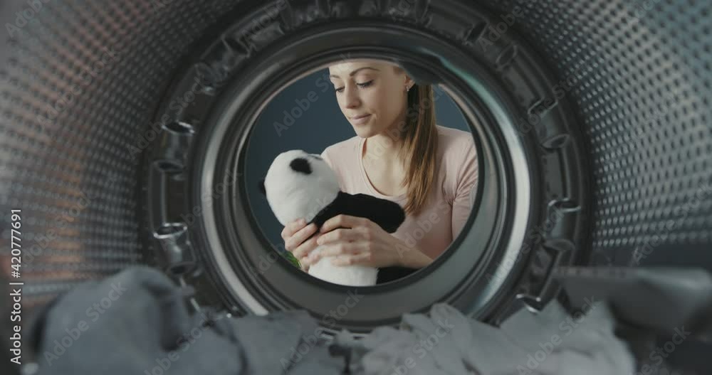 Woman opens the washing machine door and takes a freshly washed plushie