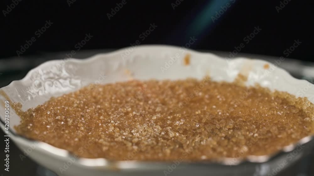 Caramelizing sugar on the top of creme brulee dessert using gas torch Caramelizing sugar on the top of creme brulee dessert using gas torch