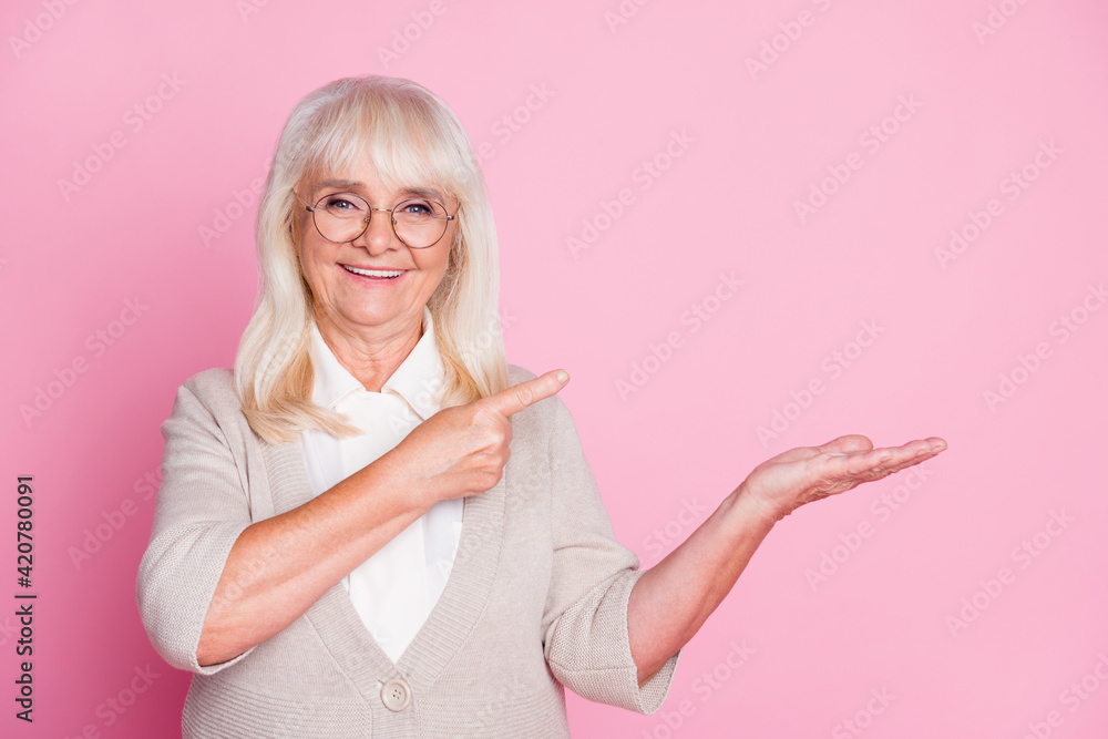 Obraz premium Photo portrait of woman pointing finger at blank space holding in hand isolated on pastel pink colored background