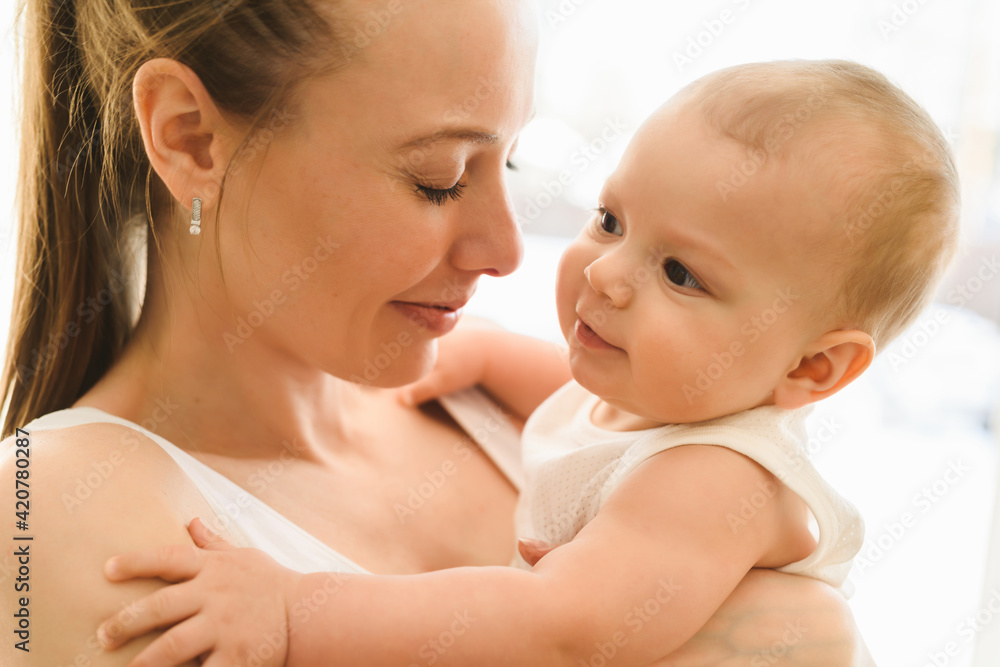 Mother and baby close-up. Mom holds the child in her arms, hugs him and kisses him. Happy family concert Mother and baby close-up. Mom holds the child in her arms, hugs him and kisses him. Happy family concert