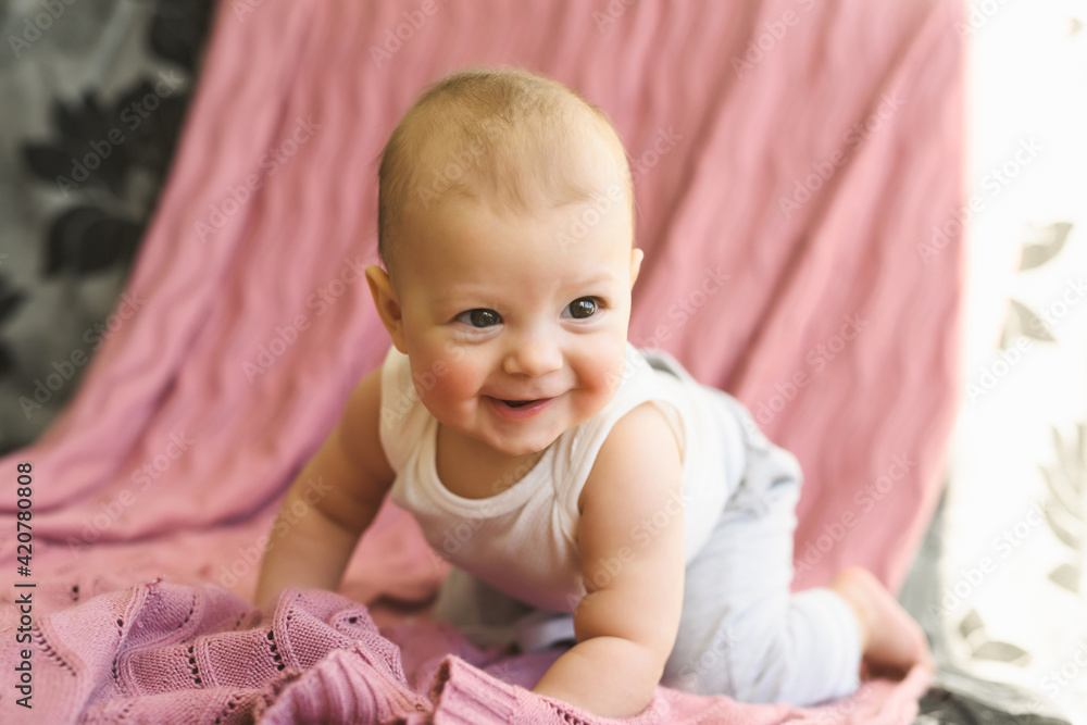 Portrait of a child, a six-month-old baby crawling on the couch and smiling. Childhood and Parenthood concept Portrait of a child, a six-month-old baby crawling on the couch and smiling. Childhood and Parenthood concept