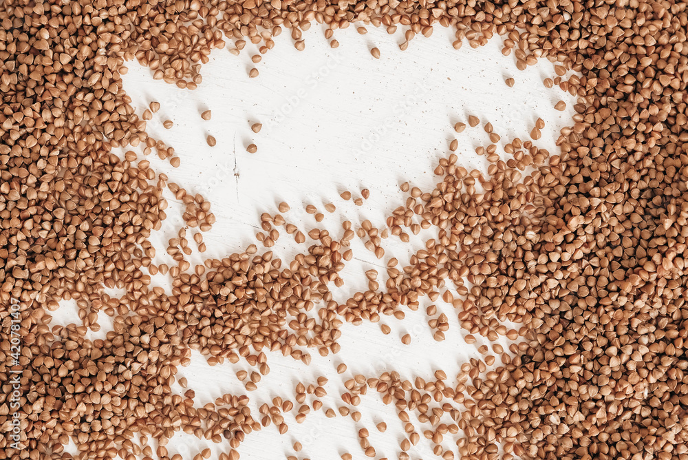 Buckwheat is randomly scattered on a white background. Top view. Copy, empty space for text Buckwheat is randomly scattered on a white background. Top view. Copy, empty space for text