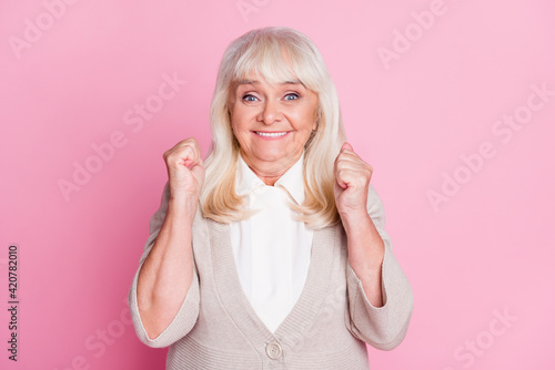 Photo portrait of excited woman celebrating isolated on pastel pink colored background