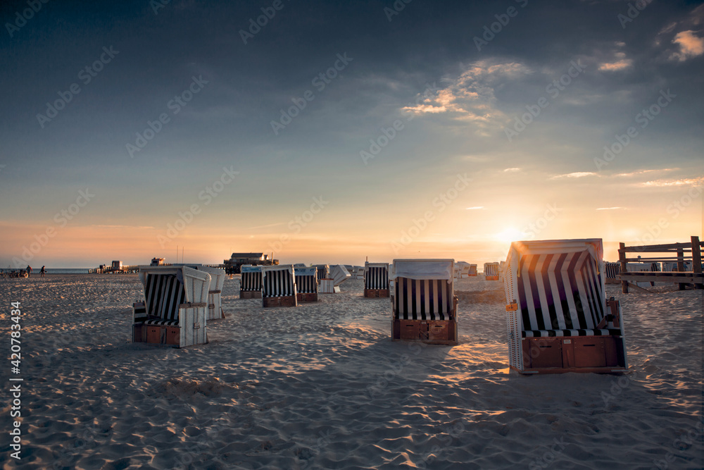 Group of roofed wicker beach chairs on sand beach during sunset. Beach equipment at holiday resorts. Group of roofed wicker beach chairs on sand beach during sunset. Beach equipment at holiday resorts.
