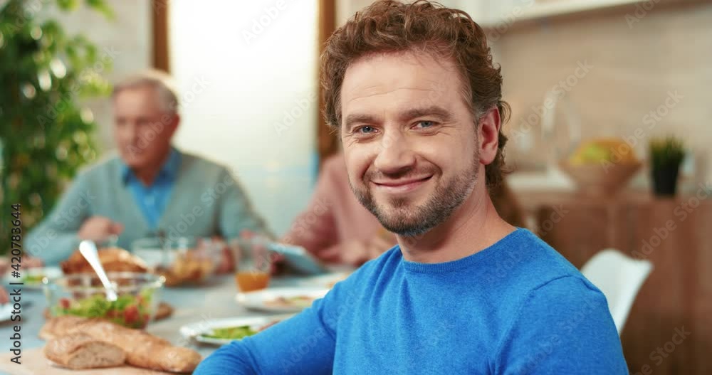 Close up portrait of happy successful man on family background at festive table looking at camera and smiling. Close up portrait of happy successful man on family background at festive table looking at camera and smiling.