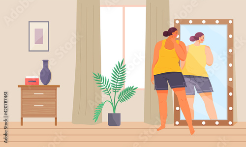 Woman in sportswear looking at reflection in mirror. Unhappy plump girl standing in front of mirror