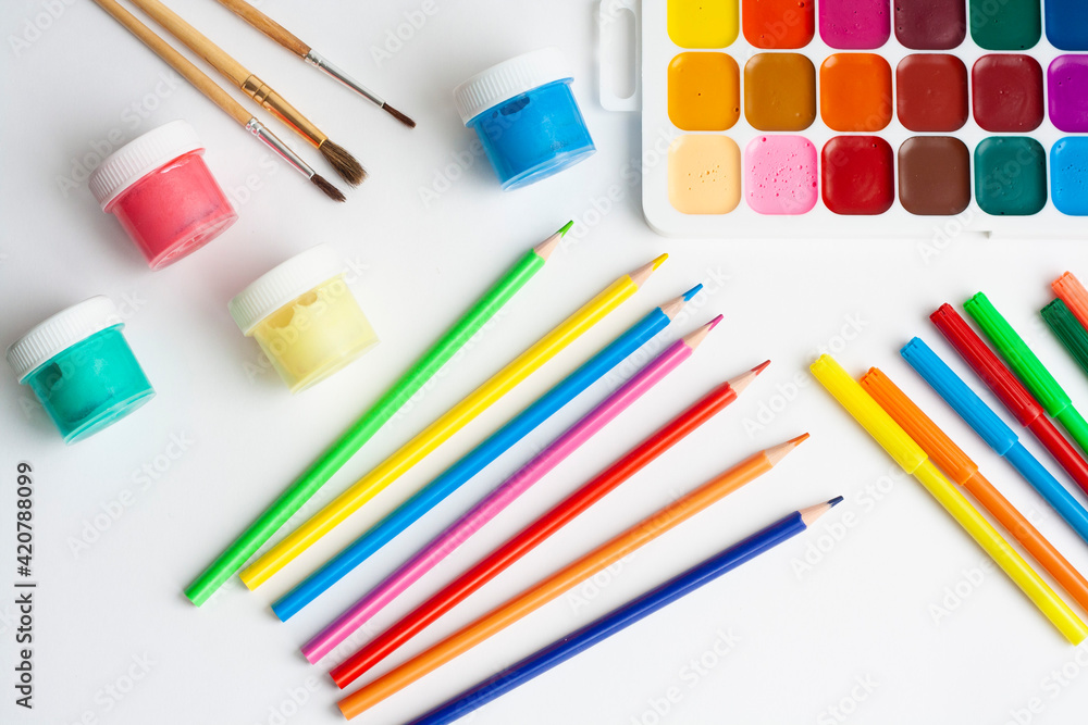 Naklejka premium Layout drawing, paints, brushes, palette, pencils and markers on a white background, top view