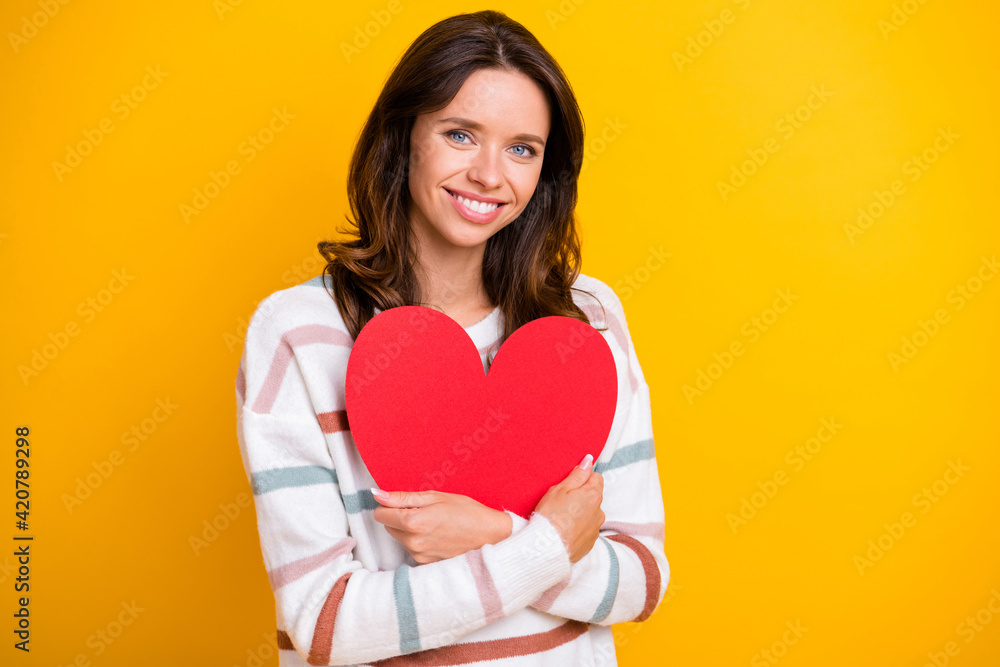 Portrait of attractive affectionate cheerful girl hugging heart shape amour isolated over bright yellow color background Portrait of attractive affectionate cheerful girl hugging heart shape amour isolated over bright yellow color background