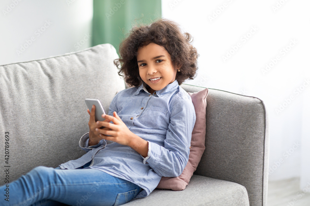 Black girl using her cell phone resting on sofa Black girl using her cell phone resting on sofa