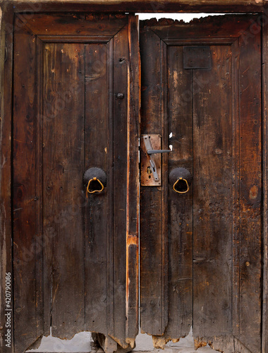 old brown rural broken double door of a village house with doorknob and knocker - abandoned architecture 
