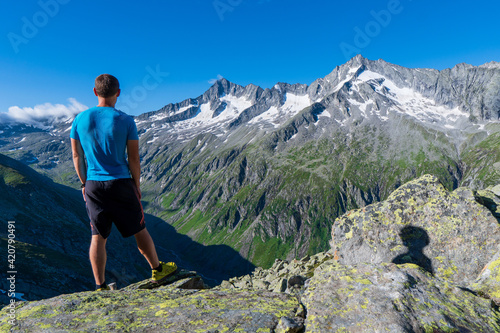 Hiking in the incredible jurassic wild landscape of green mountains, among glaciers and volcanoes. Adventurous man is on top of the mountain in Austria