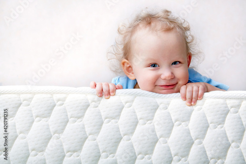 Baby on the bed mattress close-up. The sidewall of the mastras is stitched with finishing lines.