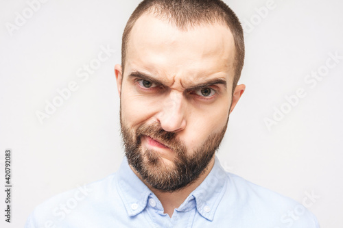 Dissatisfied bearded man pursed his lips, white background, close-up