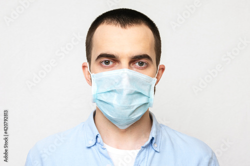 Young man wears a medical mask  white background  portrait  close-up