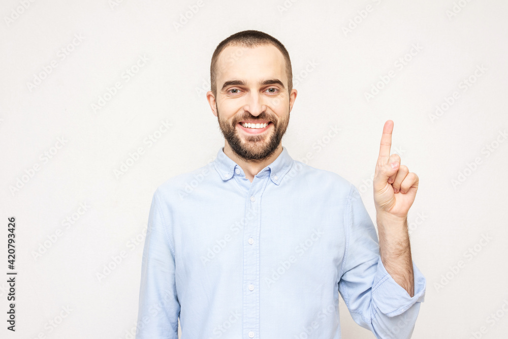 Fototapeta premium Handsome bearded raises his index finger, man has an insight or a good idea, a white background, copy space