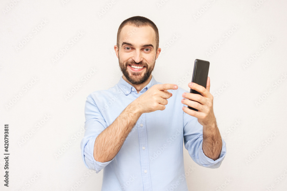 Happy bearded points the finger at phone, portrait, white background Happy bearded points the finger at phone, portrait, white background