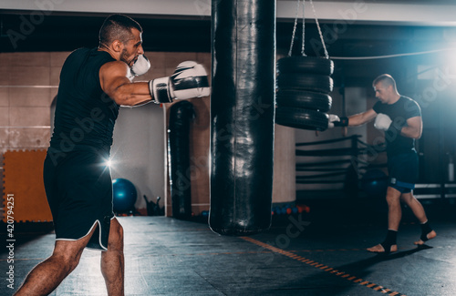 Strength male boxer training with punching bag. Boxing exercise