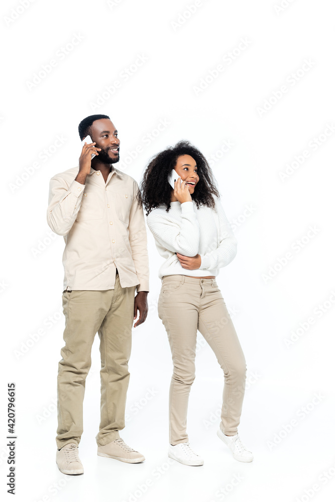 happy african american couple talking on mobile phones and looking away on white happy african american couple talking on mobile phones and looking away on white