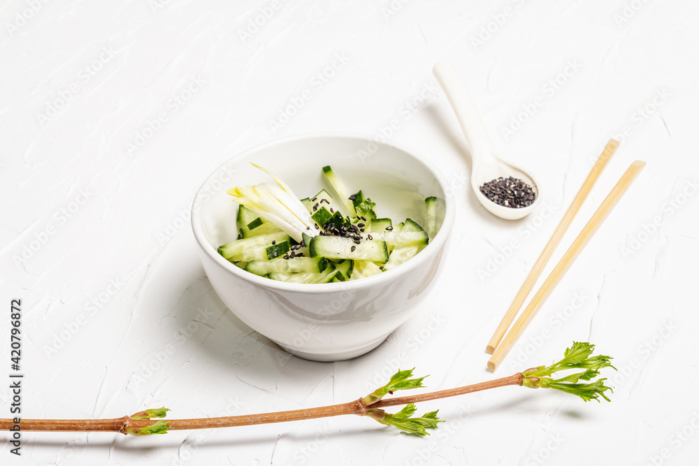 Fresh cucumber salad with sesame seeds in a white ceramic bowl Fresh cucumber salad with sesame seeds in a white ceramic bowl