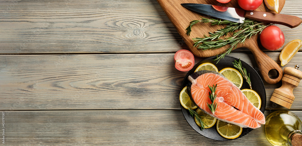 Flat lay composition with raw salmon steak and ingredients for cooking on the background of a wooden table with a copy space. Flat lay composition with raw salmon steak and ingredients for cooking on the background of a wooden table with a copy space.