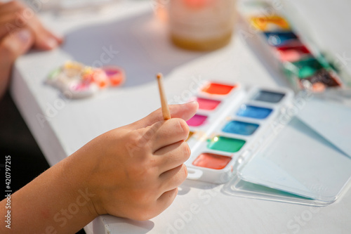 A child draws with colorful watercolor paints.