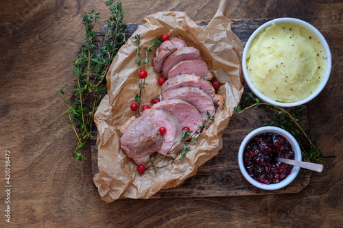 Baked  duckbreast with lingonberry sauce, thyme, mashed potatoes on a wooden table. Top view. photo