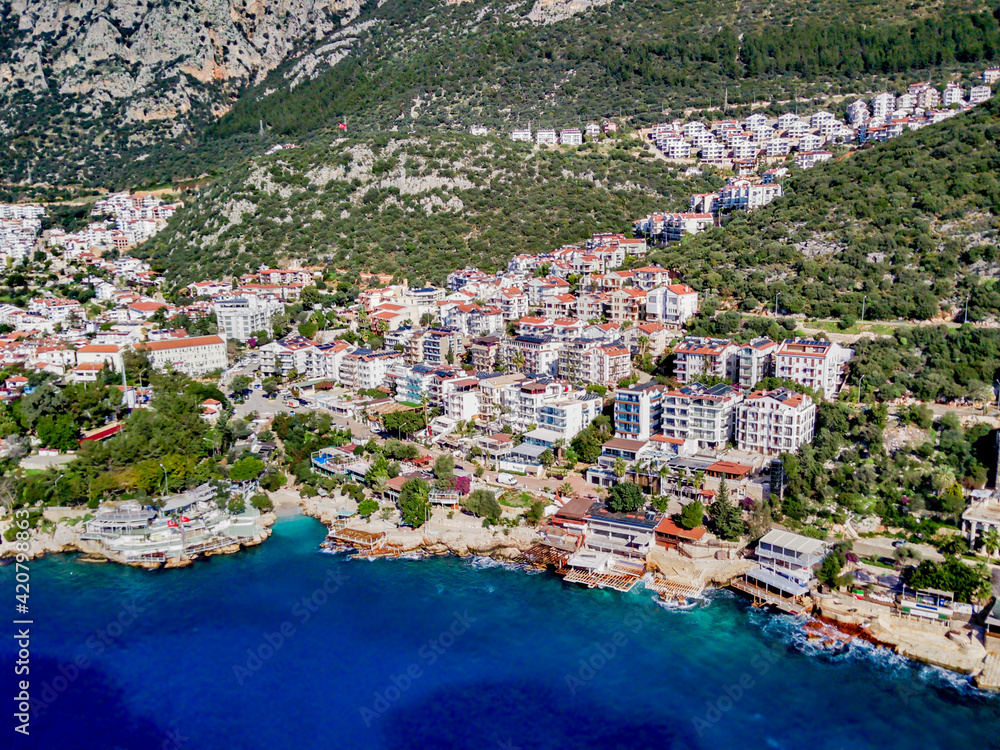 The top view from the drone of Kas resorts and city with amazing blue and clear lagoon and yachts in Mugla province of Turkey