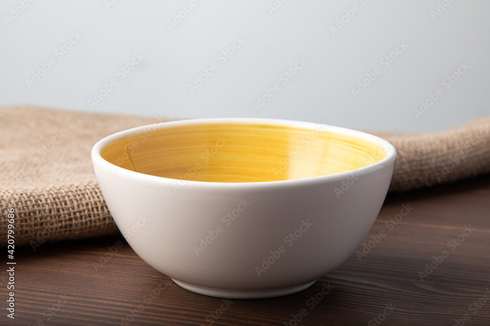 Empty white bowl with hand painted yellow inside. Isolated on wooden background Empty white bowl with hand painted yellow inside. Isolated on wooden background