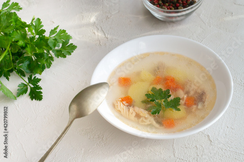 Clear fish soup with pieces of vegetables and salmon with spices in a white bowl on a white plate. Healthy nutrition concept. Top view. Horizontal orientation. photo