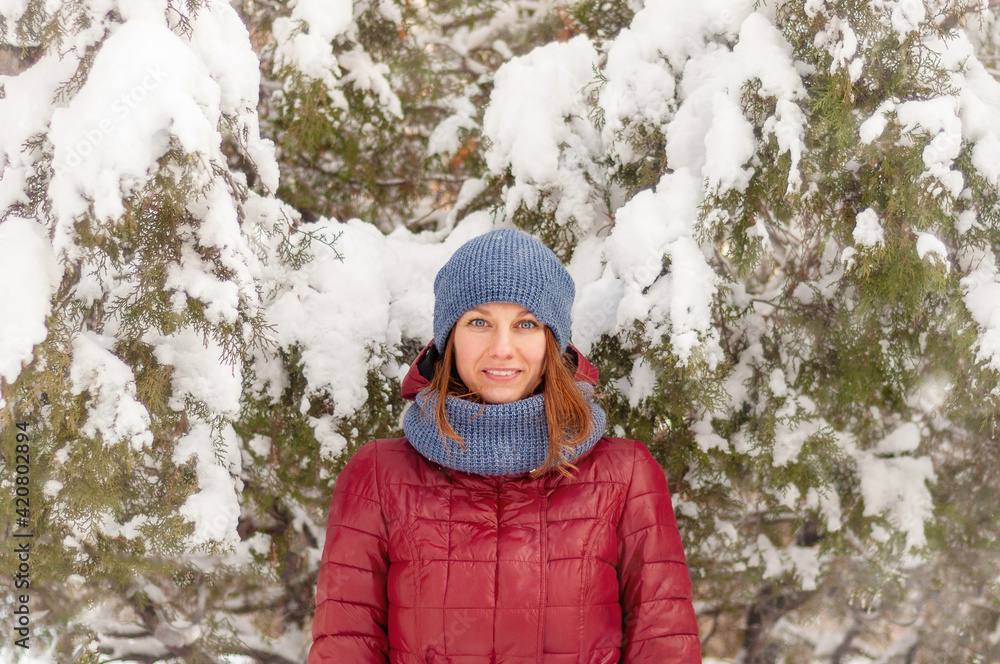 Obraz premium Winter portrait of a girl. Girl in warm clothes. Portrait of a woman in a winter park.