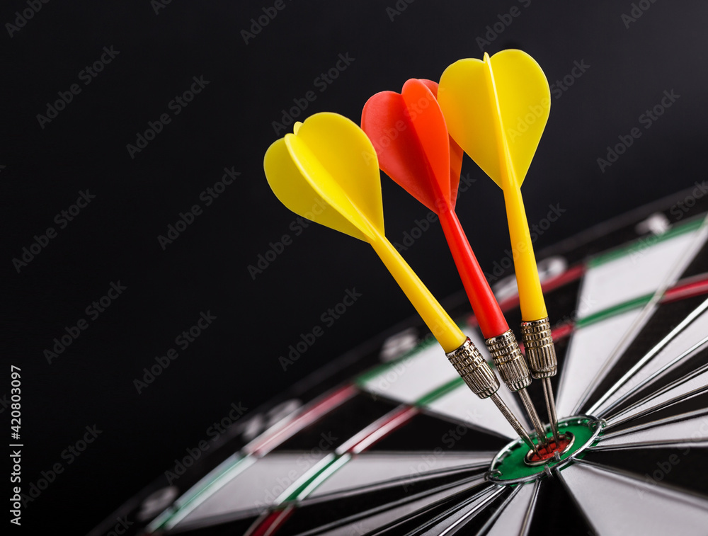 Darts board with red and yellow darts arrows on center of dartboard. Targeting, business and success concept. Darts board with red and yellow darts arrows on center of dartboard. Targeting, business and success concept.