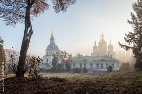 Orthodox church in the morning fog at dawn in the middle of the park photo