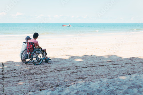 Asian special child on wheelchair is fun, playing and exercise activity on sea beach at summer, Lifestyle of disability child, Life in the education age, Happy disabled kid in travel concept.