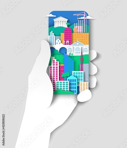 Hand holding mobile phone with city elements, urban landscape. Vector illustration in paper art style.
