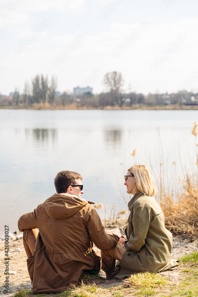 cute couple kissing at riverside sitting on the ground