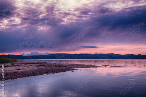 Purple sunset over Vejle Fjord in Denmark. Calm surface waters, surrounded by low forested hills. Beautiful landscape of the Jutland Peninsula.