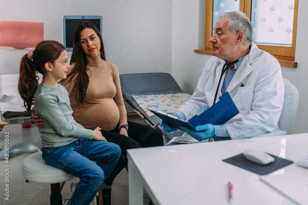 Fototapeta premium Male doctor in white coat examining his little patient in clinic office